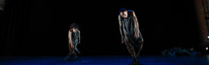 A male (Shinichi Iova-Koga) and female (Dana Iova-Koga) in mud and upside down grey hoodies, tipping sideways.